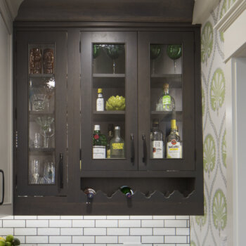 A wine and stemware display cabinet with an open wine bottle rack at the bottom and a cabinet above for glassware.